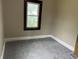 A bright bedroom with gray carpeting, a large window, neutral paint and a white baseboard at 1020 E 30Th St, Anderson, IN 46016