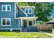 Charming blue home with a covered porch, front yard, and lush greenery at 1034 N Tacoma Ave, Indianapolis, IN 46201