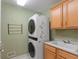 Functional laundry room with stacked washer/dryer and built-in sink and storage at 11065 Spice Ln, Fishers, IN 46037