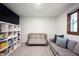 Well-lit bedroom with crib, gray couch, and storage next to the window at 11423 Atlantic Rd, Fortville, IN 46040