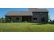 Back exterior view of home featuring a screened porch, patio area, and a well-maintained lawn at 11875 W 700 S, Columbus, IN 47201