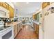 Open kitchen layout with wood cabinets, white appliances, and a view into the dining and living areas at 11875 W 700 S, Columbus, IN 47201