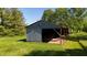 Practical outbuilding with open sides for easy access, set amidst a backdrop of lush greenery and mature trees at 11875 W 700 S, Columbus, IN 47201