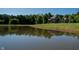 Tranquil pond reflecting a home surrounded by lush greenery under a clear blue sky at 11875 W 700 S, Columbus, IN 47201