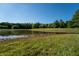 Scenic pond reflecting a beautiful home surrounded by lush greenery under a clear blue sky at 11875 W 700 S, Columbus, IN 47201