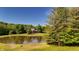 Scenic view of a tranquil pond with the home nestled among mature trees in the background at 11875 W 700 S, Columbus, IN 47201