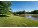 Scenic view of a serene pond surrounded by lush greenery and mature trees on a clear, sunny day at 11875 W 700 S, Columbus, IN 47201