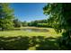 Picturesque view of a backyard pond surrounded by lush greenery and a distant shed at 11875 W 700 S, Columbus, IN 47201