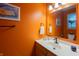 Vibrant bathroom with orange walls, a white sink and vanity, complemented by a nautical-themed decor at 13271 Aquamarine Dr, Carmel, IN 46033