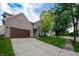 Charming brick home with a manicured lawn, a paved driveway, and established trees in a serene setting at 13271 Aquamarine Dr, Carmel, IN 46033