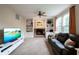 Comfortable living room features built-in shelving, a fireplace, a leather sofa, and large windows at 13271 Aquamarine Dr, Carmel, IN 46033
