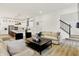 Open-concept living room flowing into a white kitchen, featuring modern furnishings and hardwood floors at 1364 Chatham Hills Blvd, Westfield, IN 46074