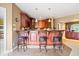 Charming wet bar with rich wood cabinetry, stylish lighting, and seating offers a perfect spot to enjoy drinks and conversation at 14711 Macduff Dr, Noblesville, IN 46062