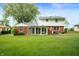 Expansive backyard features a well-maintained lawn, mature trees, and a brick house with a sunroom at 1495 E 240 N, Anderson, IN 46012