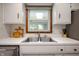 Bright kitchen sink area with white cabinets, a window overlooking the backyard, and modern fixtures at 1495 E 240 N, Anderson, IN 46012