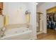 Bathroom featuring a tub, shower, storage shelves, tile accents, and a doorway to a walk-in closet at 16126 Hymera Green, Westfield, IN 46074