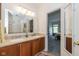 Bright bathroom with double sinks, wooden cabinets, granite countertops, and an open doorway to the main bedroom at 16126 Hymera Green, Westfield, IN 46074