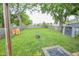 Expansive backyard with lush grass, a storage shed, a playground, and a well-maintained wooden fence at 2235 N Kenwood Ave, Indianapolis, IN 46208