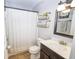 Cozy bathroom features a shower with a white curtain, toilet, wood floor, and a decorative shelf at 2235 N Kenwood Ave, Indianapolis, IN 46208