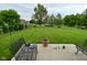 Green backyard with trees, black fence, and patio seating at 2330 Oak Dr, Clayton, IN 46118