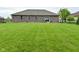 Well-manicured lawn in the backyard, with a brick home and sliding glass door entry at 2330 Oak Dr, Clayton, IN 46118