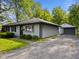 Exterior showcasing a single-story home with a detached garage, gray siding, and a driveway at 3627 N Brentwood Ave, Indianapolis, IN 46235