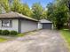 Exterior showcasing a detached garage, gray siding, and a driveway at 3627 N Brentwood Ave, Indianapolis, IN 46235