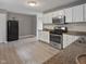 An open kitchen features white cabinets, stainless appliances, granite countertops, and light wood floors at 3627 N Brentwood Ave, Indianapolis, IN 46235