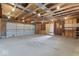 Large garage featuring high ceilings with exposed beams, unfinished walls and a gray rolling garage door at 3716 W 16Th St, Indianapolis, IN 46222