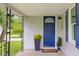 Close-up view of a blue front door with a covered porch, enhanced by plants and black railings at 425 Patterson Rd, Columbus, IN 47203