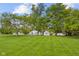 View of a green lawn and mature trees leading up to a white house with blue trim and a detached garage at 425 Patterson Rd, Columbus, IN 47203