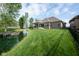 Expansive backyard with a well-manicured lawn, a tranquil pond, and a view of the home's exterior at 4359 Prairie Falcon Dr, Zionsville, IN 46077