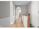 Upstairs hallway with hardwood floors, white wainscoting, arched doorways, and white railing at 4359 Prairie Falcon Dr, Zionsville, IN 46077