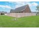 Spacious fenced backyard with green grass, a fire pit, and a brick home at 4399 Summerhaven Dr, New Palestine, IN 46163