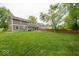 Expansive backyard with a lush green lawn, mature trees, and views of the home's exterior at 506 Deerberry Dr, Noblesville, IN 46062