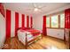 Bright bedroom with hardwood floors, ceiling fan, and large windows with red accents and striped walls at 506 Deerberry Dr, Noblesville, IN 46062