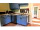Traditional kitchen featuring blue cabinets, stainless steel appliances, and a view into an adjacent room at 518 N Emerson Ave, Indianapolis, IN 46219