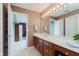 Bright bathroom has a dual-sink vanity with wood cabinets, a large mirror and overhead lighting at 5251 Apache Moon, Carmel, IN 46033