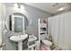 Charming bathroom with a pedestal sink, round mirror, and organized shelving, creating a functional space at 5758 N 900 W, Thorntown, IN 46071