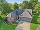 Aerial view of a brick home featuring a landscaped yard, and a two-car garage with ample parking at 7061 Woodgate Cir, Fishers, IN 46038