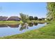 Scenic backyard with a tranquil pond, reflecting the surrounding homes and lush green landscape at 7061 Woodgate Cir, Fishers, IN 46038