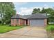 Charming brick home featuring an attached garage and a well-manicured lawn, with a red front door at 7061 Woodgate Cir, Fishers, IN 46038