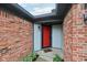 Close up of the red front door, framed by brick and grey siding, complemented by garden plants at 7061 Woodgate Cir, Fishers, IN 46038