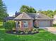 This home boasts attractive brick accents, manicured landscaping, and a gray two-car garage at 7061 Woodgate Cir, Fishers, IN 46038