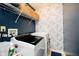 A laundry room with modern washer and dryer, wire shelf, and floral wallpaper at 73 Spring Lake Dr, Westfield, IN 46074