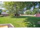 Large backyard with a mature tree, green lawn, screened-in porch, and a storage shed at 7450 Cotherstone Ct, Indianapolis, IN 46256