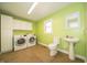 Well-lit laundry room boasts a full-size washer and dryer, complemented by a utility sink and storage cabinets at 7450 Cotherstone Ct, Indianapolis, IN 46256
