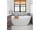 Inviting white soaking tub with wood caddy and natural light streaming in from the window at 8555 S County Road 375 E, Mooresville, IN 46158