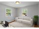 Staged bedroom showcasing hardwood floors, neutral walls, two windows, sofa, and office desk at 895 W Poplar St, Zionsville, IN 46077