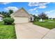 Home featuring a two-car garage and long driveway, adjacent to a landscaped yard and pond with fountain at 896 Fairfield Dr, Greenfield, IN 46140